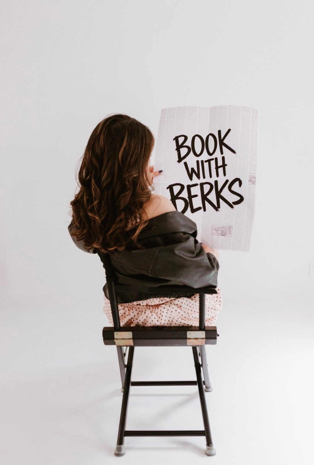 Berkeley of The Berkeley Blend holding a Book with Berks sign, with her long brunette waves
